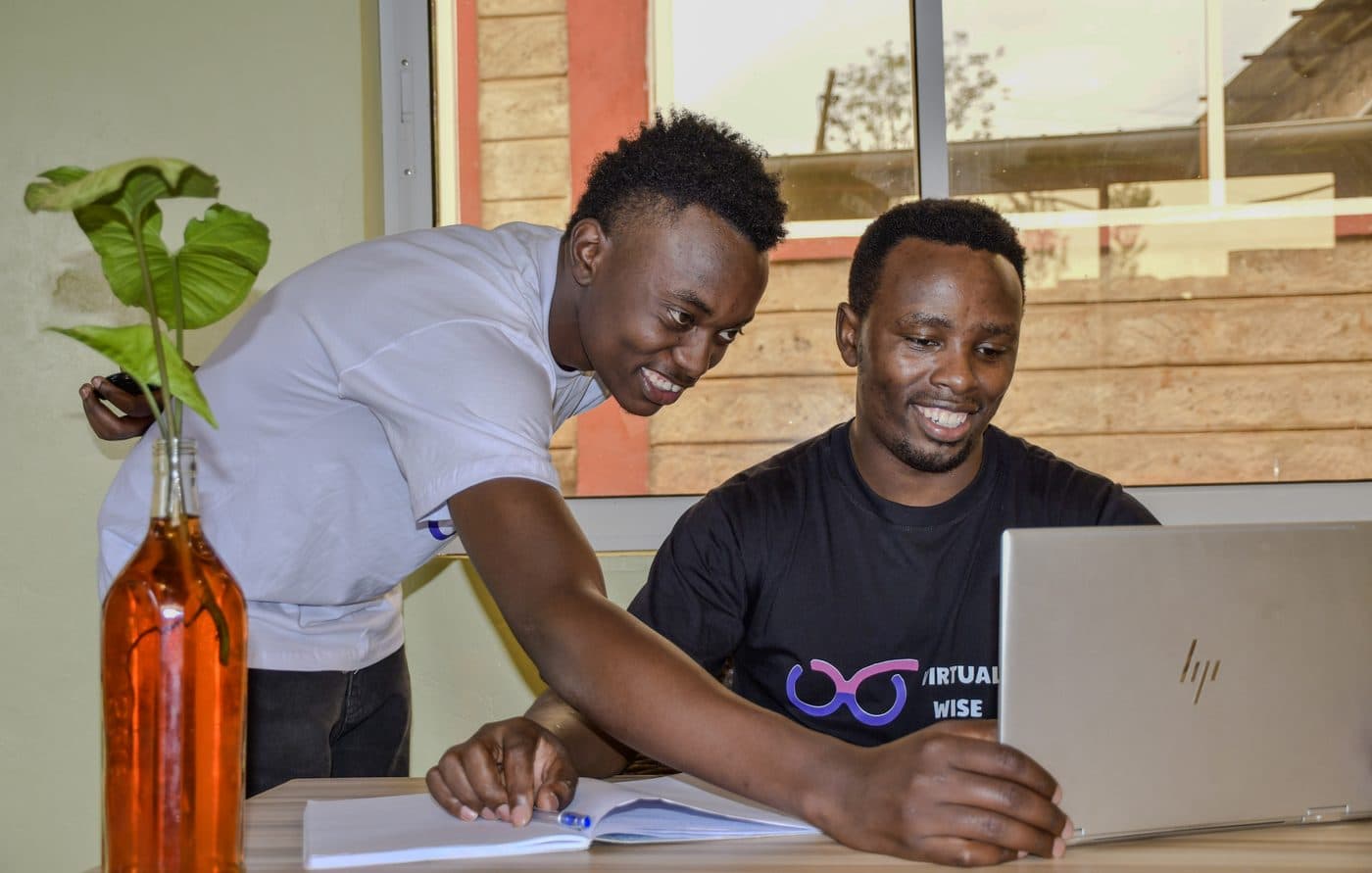 Two Virtual Wise team members working through a question together at a laptop