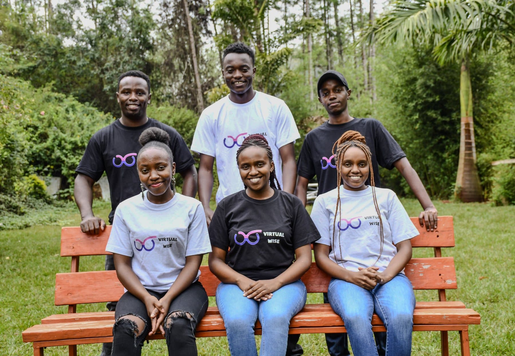 The Virtual Wise team in branded t-shirts on a bench in Kenya